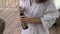 Young woman in bathrobe opening bottle of champagne