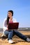 Young woman on the beach with laptop