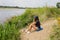 Young woman on the beach river looking on the fishing rod