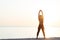 Young woman at the beach stretching after workout