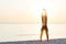 Young woman at the beach stretching after workout