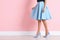 Young woman with beautiful long legs in stylish outfit near color wall, closeup