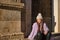 Young woman, beautiful, straight brown hair, leather pants, sweater, coat and wool hat, sitting on a step pensive and relaxed.