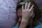 Young woman in bed and holding her head near mercury thermometer