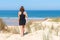 Young woman from behind walking in sand dunes of Atlantic ocean in cap ferret France