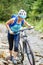 Young woman with bicycle wade the mountain creek