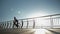 Young woman bicyclist in helmet is pedaling on road aero bike on pedestrian bridge at sunrise. Female hipster rider is cycling on