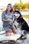 Young woman and big dog husky is sitting outdoors