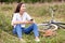 Young woman biker holding a smartphone and sitting on a grass