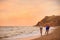 Young woman in bikini and her boyfriend  on beach at sunset. Lovely couple