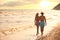 Young woman in bikini and her boyfriend walking at sunset. Lovely couple