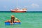 Young woman in bikini standing backwards in sea water with swimming circle