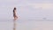 Young woman in bikini walking on sea water at sandy beach on paradise resort. Low angle view. Beautiful woman running on