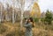 Young woman with binoculars watching birds in the autumn forest. Scientific research