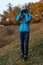 Young woman with binoculars watching birds in autumn park