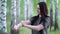 Young woman in a birch grove puts a mosquito repellent on her skin.