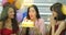 Young woman birthday girl is making wish, blowing candle on cake and clapping hands while her friends are congratulating