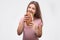 Young woman bite sandwich and look on camera. She hold it in hands. Model is hungry. Isolated on white background.