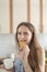 Young woman bites cracker and slyly looks at camera. Girl drinks coffee and eating cookies. Cheat meal. Vertical frame