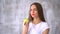 Young woman biting and eating tasty green apple. Healthy young woman eating green apple and smiling at home - indoors.