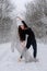 Young woman in black ballet suit plays in snowy forest with a bright cloth