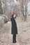 Young woman in black coat stand on path outdoor in park look back winter