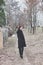 Young woman in black coat walk on path outdoor in park look back winter
