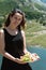 Young woman in a black dress holds a plate of fruit: pears, watermelon, grapes and figs at picnic in the mountains Montenegro.