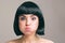 Young woman with black hair posing on camera. Expressive emotional model with bob haircut. Isolated on light background