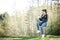 Young woman in a black jacked with coffee cup and laptop working outside in a park. Remote work. Digital work.