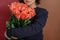 young woman in a black jacket embraces a bouquet of large roses