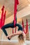 Young woman in black jumpsuit performing antigravity yoga exercise