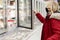 Young woman in a black medical mask in the supermarket in the frozen food department. The blonde in the red jacket. Coronavirus