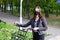 Young woman in the black protective medical mask with a bicycle in the city park
