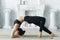 young woman in black sportswear shows yoga asanas and does pilates