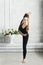 young woman in black sportswear shows yoga asanas and does pilates