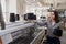 Young woman with black threads in cones in her hands near industrial knitting machines