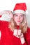 Young woman with blond hair wearing red santa hat and sweater is holding and unwrapping the gift box