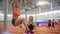 Young woman with blonde hair pulls up on the crossbar in the sports hall under the guidance of a trainer