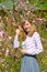 The young woman among the blossoming bushes of almonds three-blade