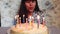 Young woman blow out candles on birthday cake, anniversary celebration