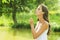 Young woman blowing dandelion in meadow. Beautiful female makes a wish on sunny summer day in park. Outdoors. Enjoy nature.