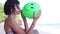 young woman blowing inflating a green balloon, young female on the beach, slow motion. Ocean, Bali, Indonesia.