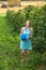 Young woman in blue dress picking blackberries