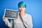 Young woman with blue fashion hair holding blackboard with strong message cover mouth with hand shocked with shame for mistake,