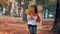 Young woman with a bouquet of yellow autumn leaves in park, enjoying leaf fall