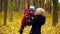 Young woman and boy 2 years have fun in the autumn park. Mom holds his son by the hands and turns around with him. A pleasant day