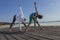 Young woman and boy doing wide legged bend on the beach