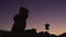 Young woman brews coffee on a gas burner in a kettle, against the backdrop of a beautiful sunset in the mountains