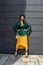 Young woman in bright clothes, yellow skirt and green jacket. Yellow socks in sandals, beret on the head, hair with the